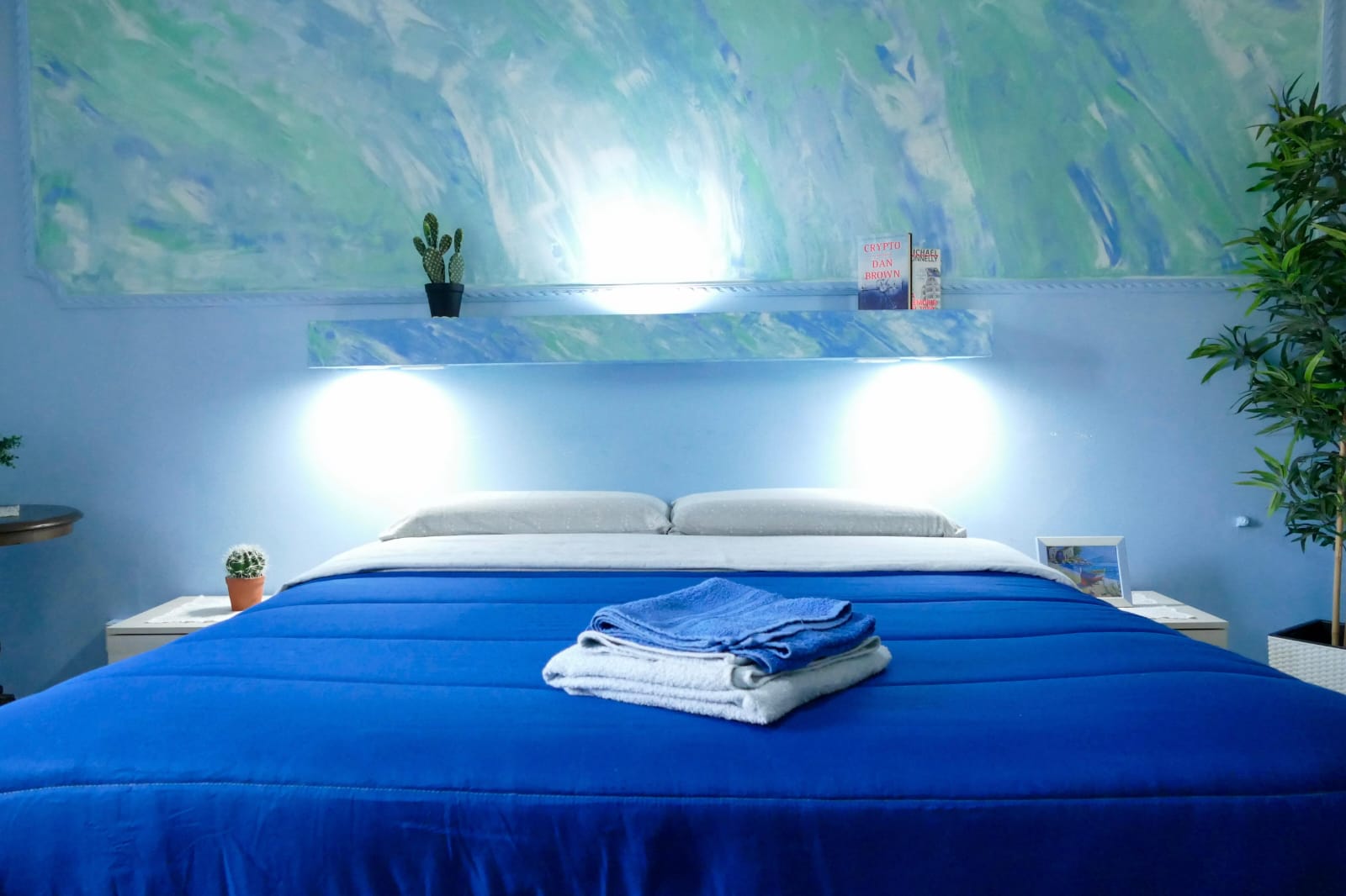 Letto matrimoniale con copriletto blu e luci da lettura