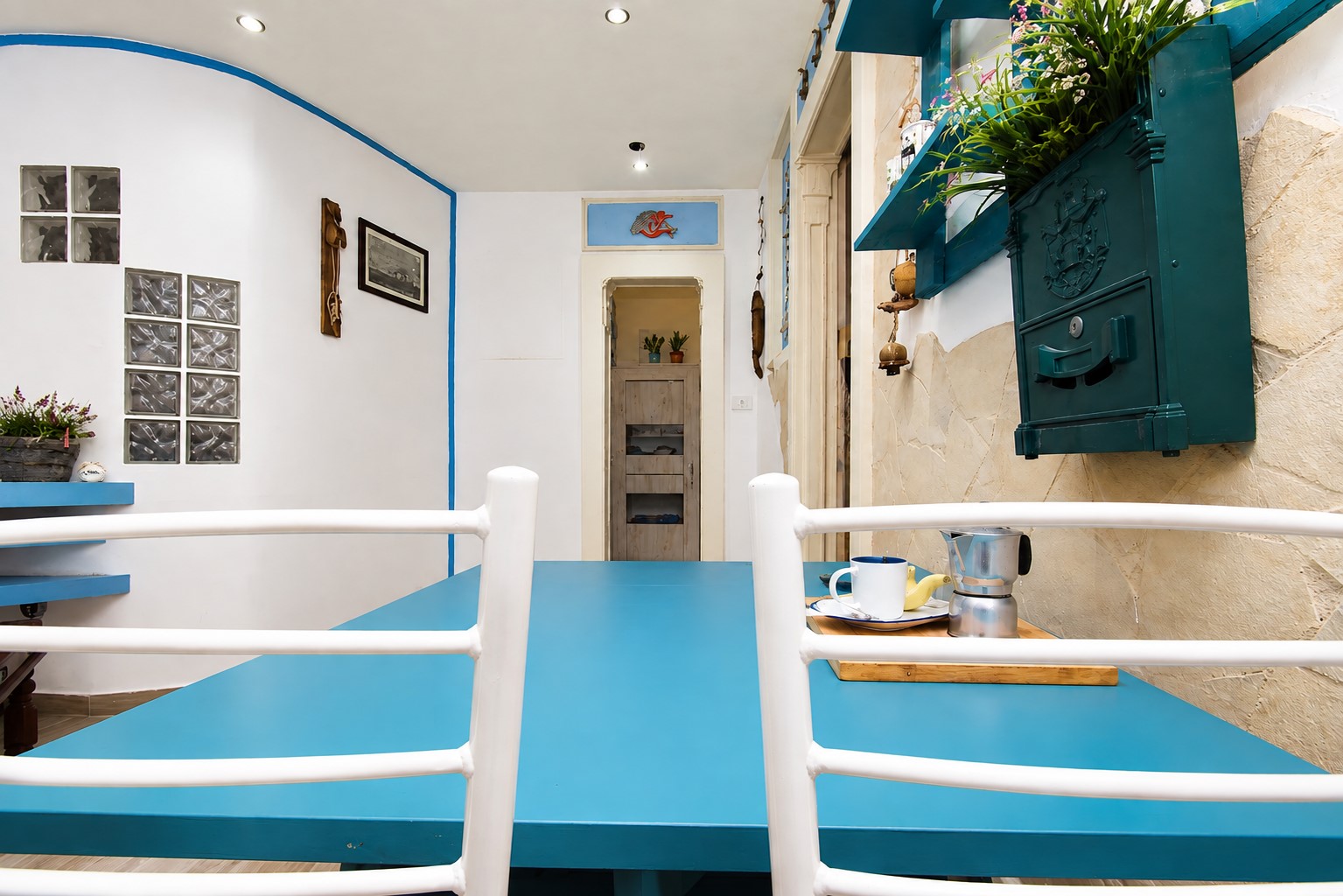Zona pranzo con tavolo azzurro e dettagli mediterranei dell'appartamento Approdo di Ulisse